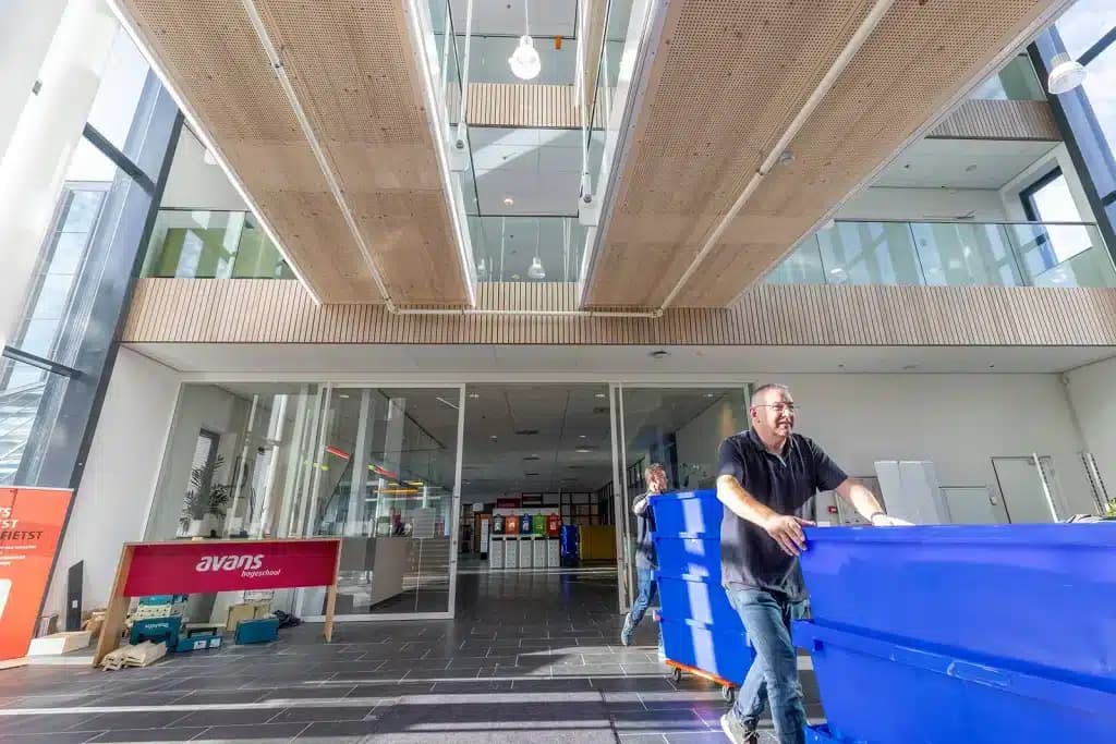 Verhuizer van Oomen rijdt een blauwe rolcontainer door de hal van Avans Hogeschool