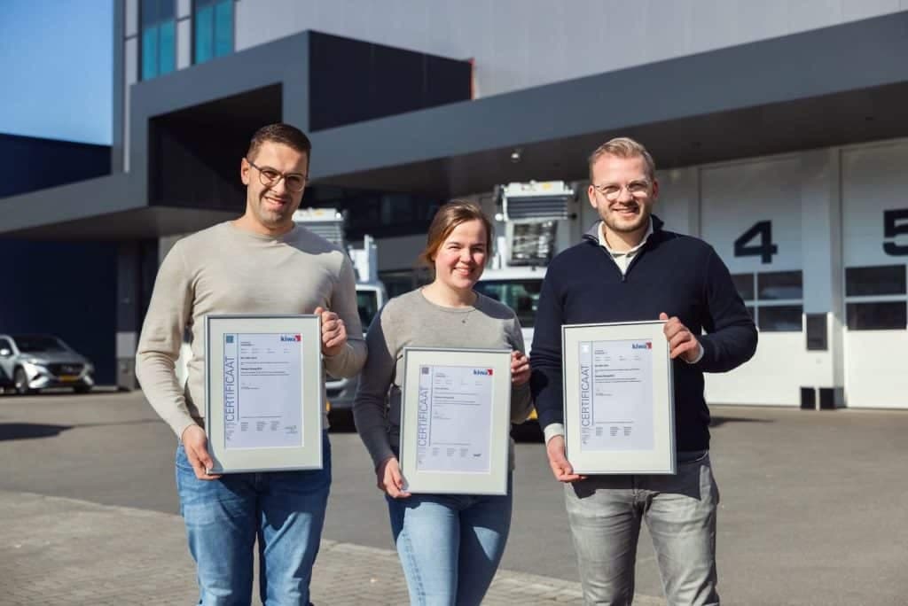 Drie Oomen-medewerkers tonen hun ISO-certificaten voor het bedrijfspand