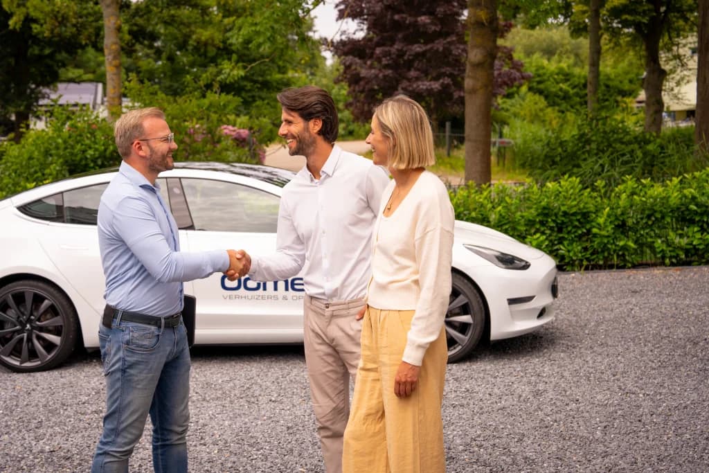 Accountmanager van Oomen begroet een stel met een handdruk bij de auto