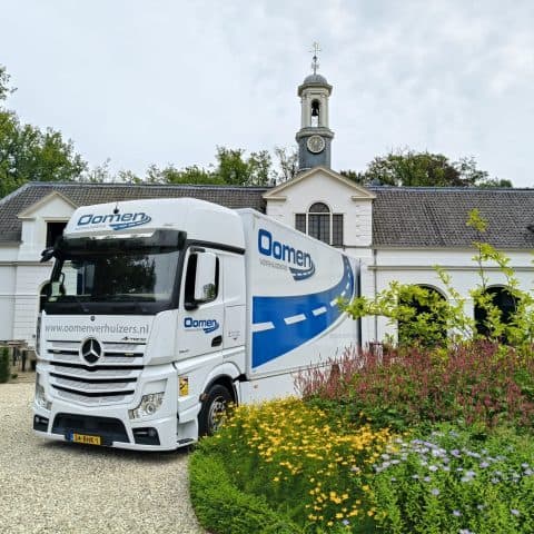 Oomen moving truck parked at an estate with a clock tower