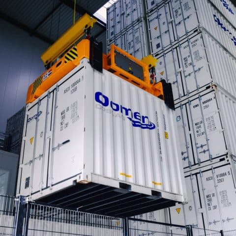 Overhead crane lifting an Oomen storage container in the storage warehouse