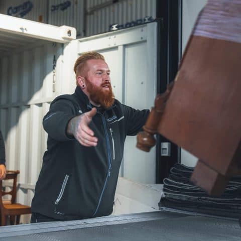 Oomen mover receiving a wooden piece of furniture at the moving truck
