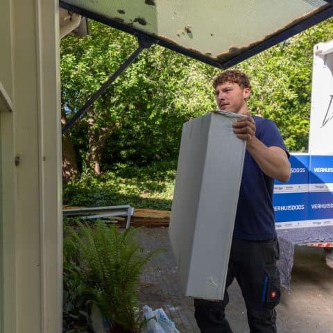 Oomen mover carrying a white cabinet to the front door