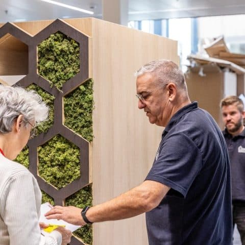 Oomen employees installing a cabinet with a moss wall during an office fit-out