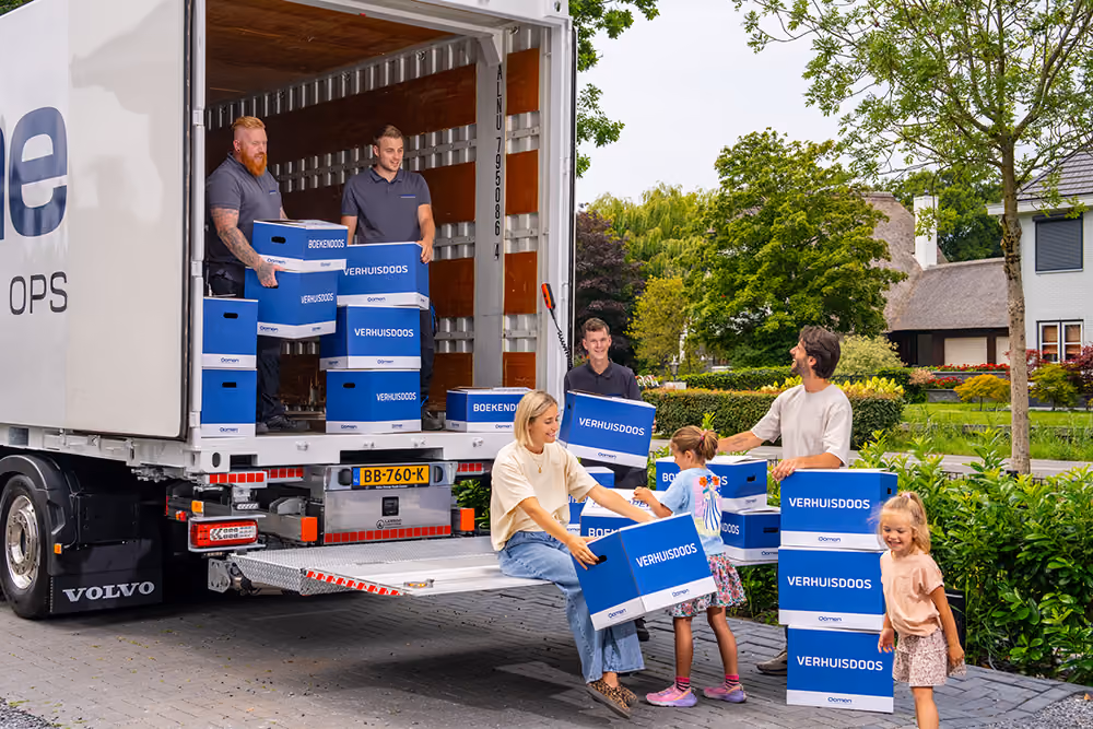 Oomen movers unloading moving boxes from the truck together with a family